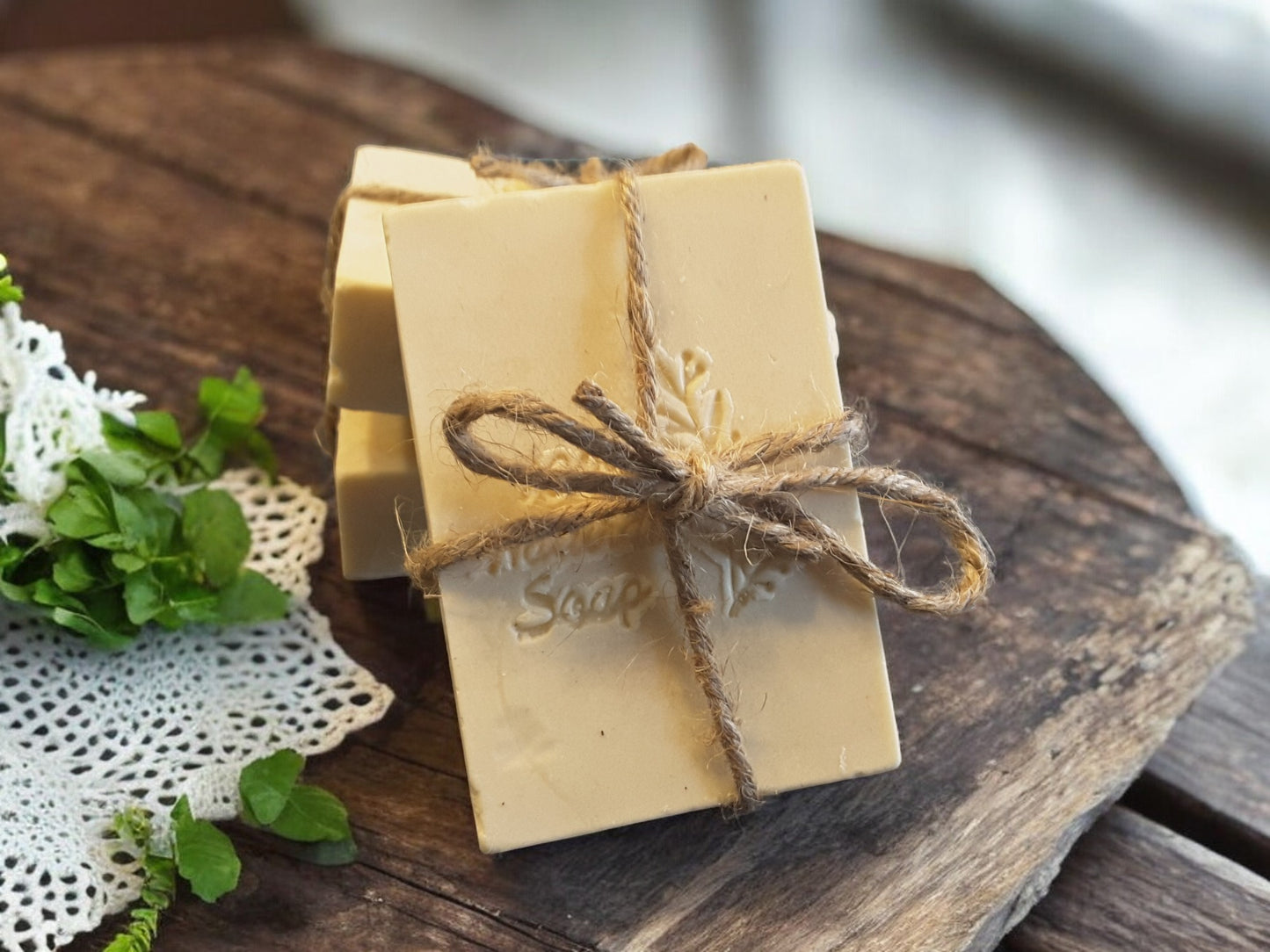 Bar of soap wrapped in twine on a wooden surface with greenery