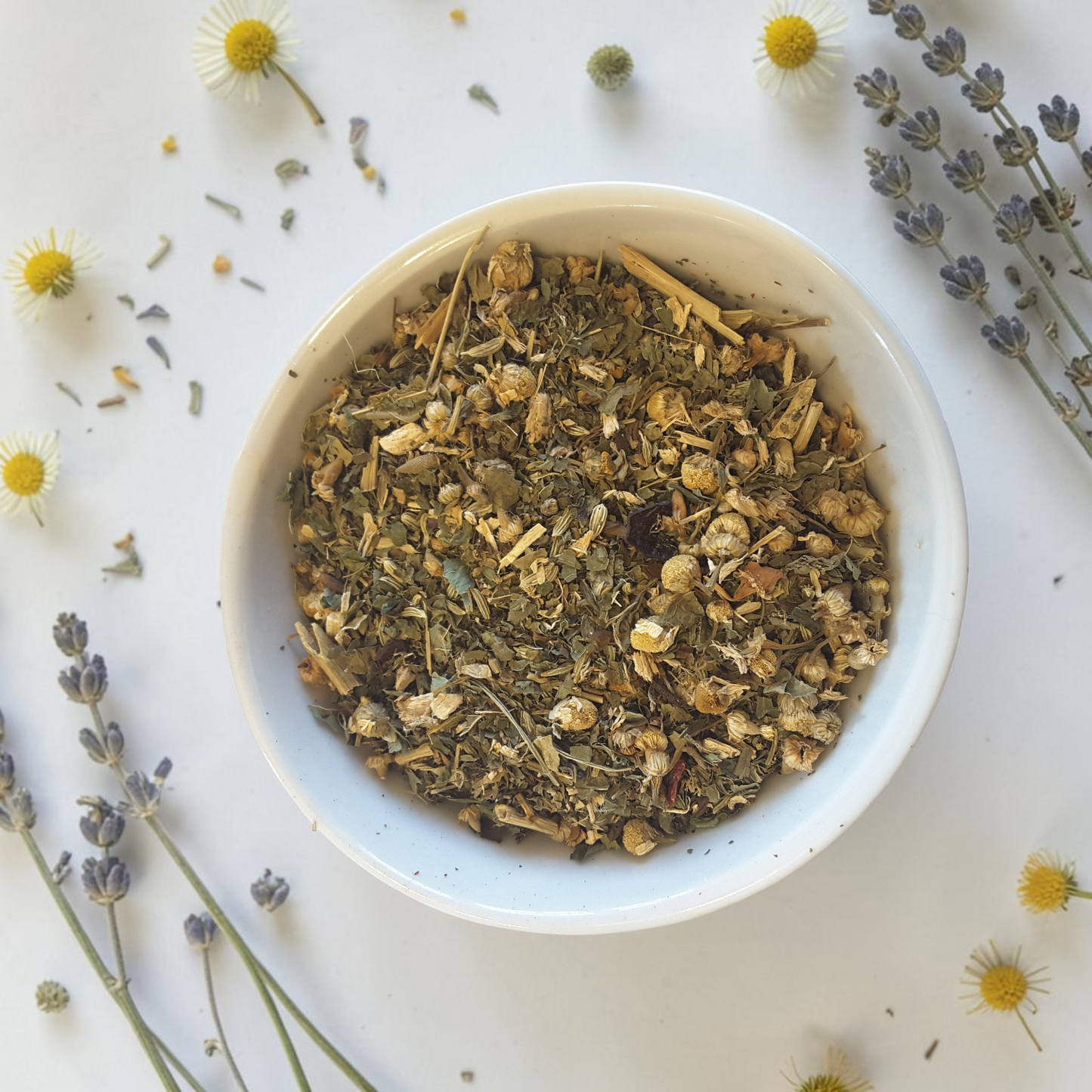 chakra balance loose leaf tea blend on a light surface with lavender and chamomile flowers.