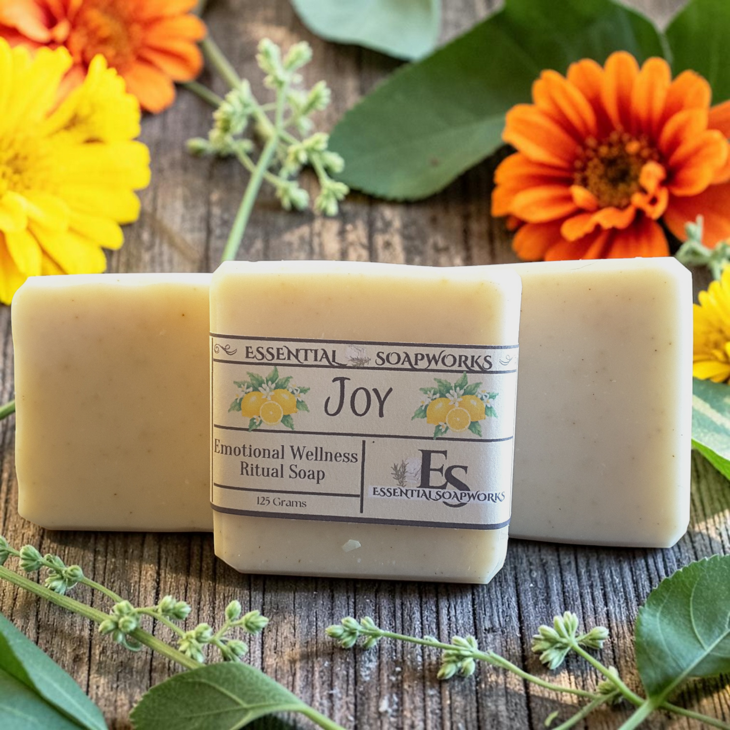 Joy Emotional Wellness Soap surrounded by yellow and orange flowers on a wooden surface