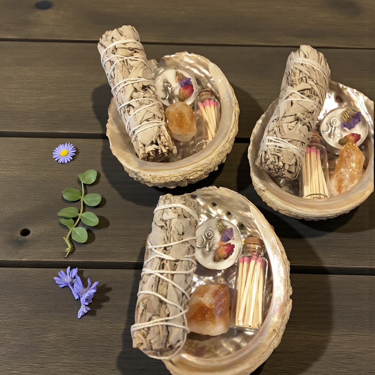 smudging kit with abalone shell, smudge sticks, matches, and citrine crystal on a wooden surface.