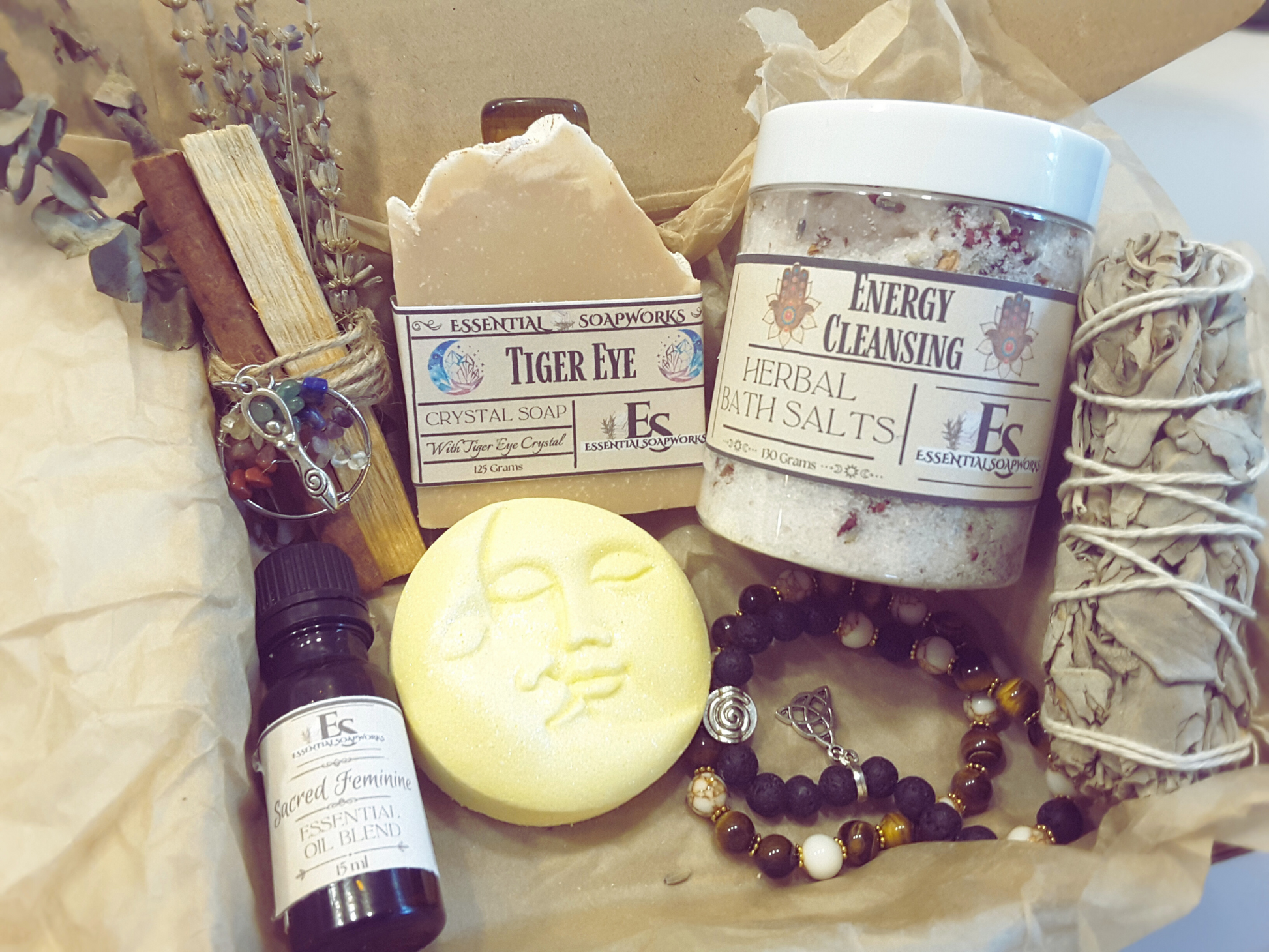tiger eye mind, body and spirit self-care kit with tiger eye crystal soap, sun and moon bath bomb, bath salts, sacred feminine essential oil blend, tiger eye bracelets with triquetra charm, white sage smudge stick and a palo santo, eucalyptus, cinnamon stick and lavender smoke cleansing bundle with a crystal tree of life charm and triple goddess charm