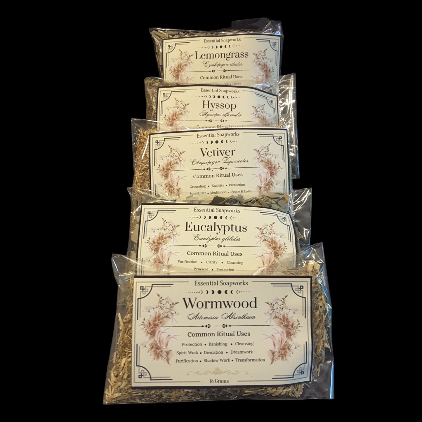 Five sealed pouches of energy cleansing herbs for witchcraft stacked vertically on a black background. The labels read Lemongrass, Hyssop, Vetiver, Eucalyptus, and Wormwood