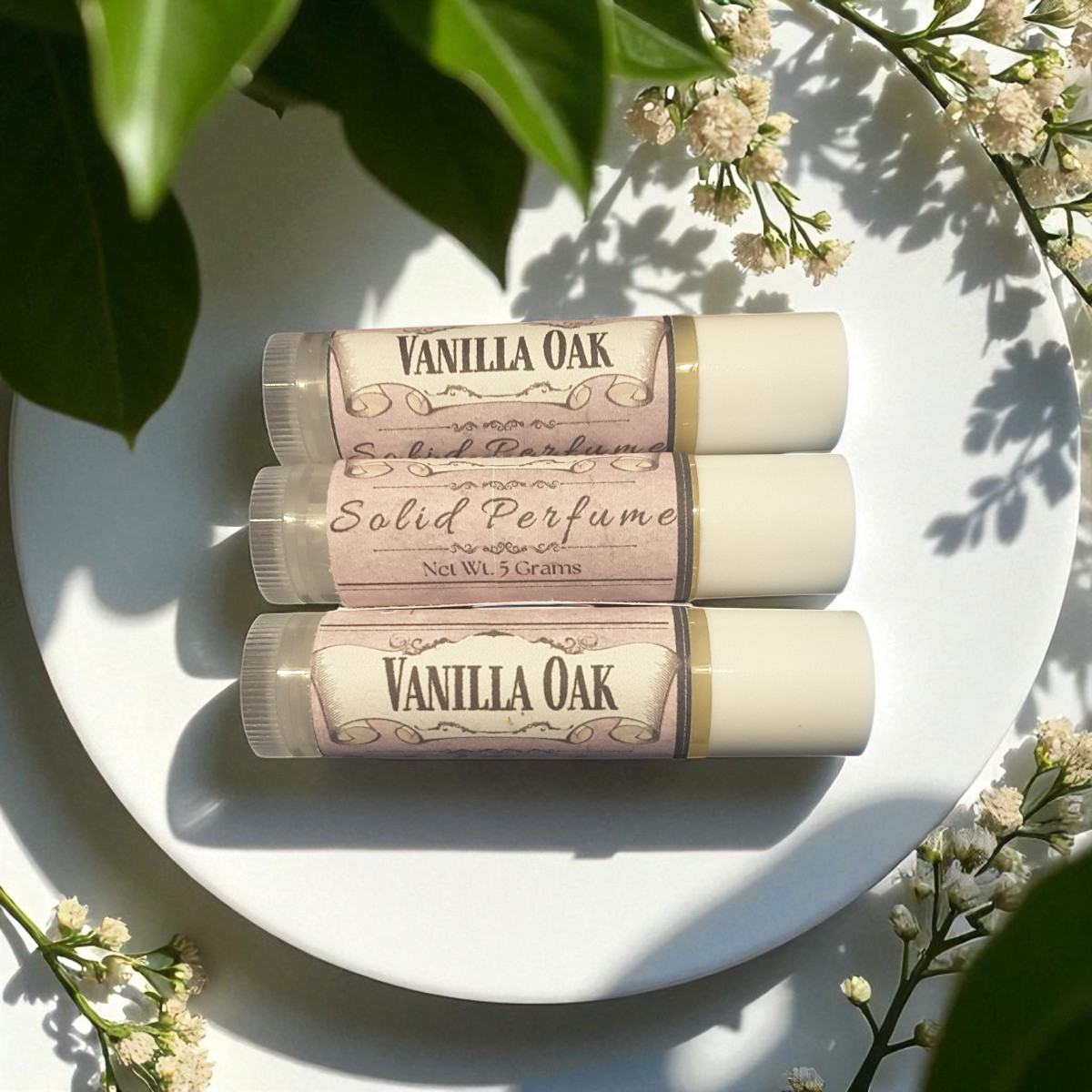 Three Vanilla Oak solid perfumes on a white plate with flowers around