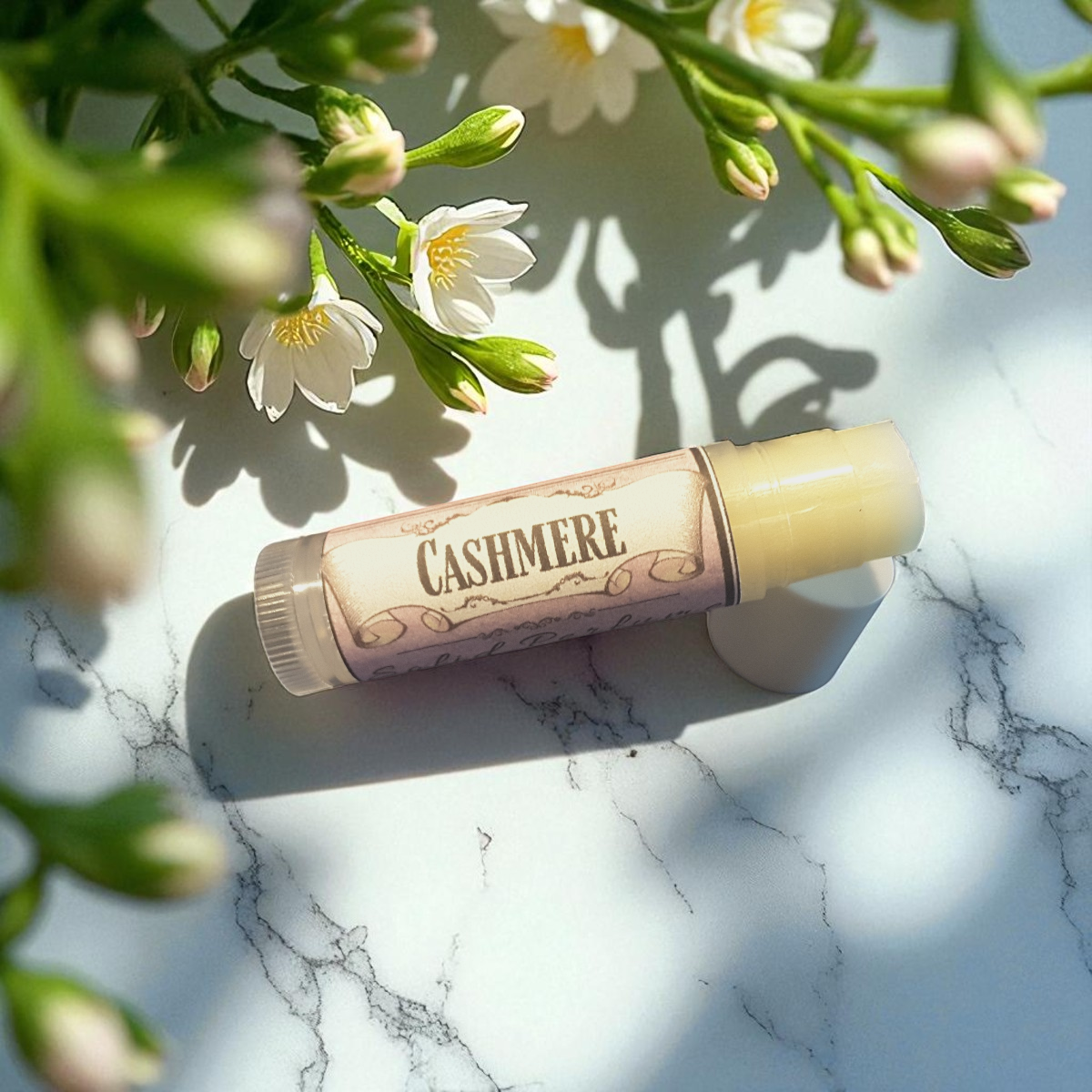 Cashmere solid perfume on a marble surface with flowers in the background