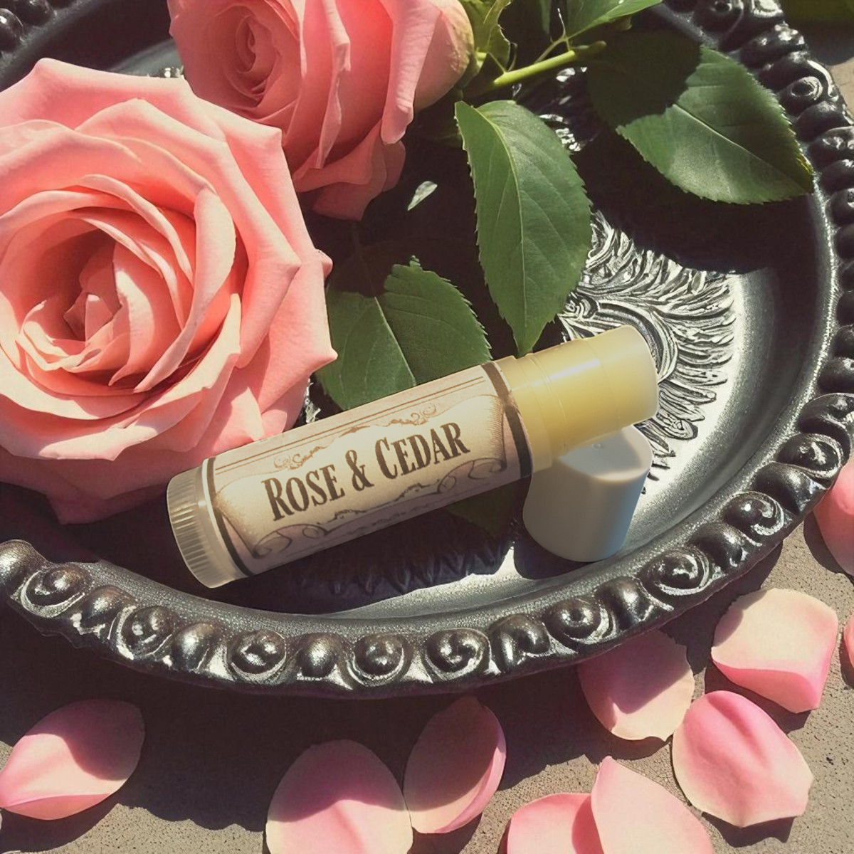 Rose & Cedar solid perfume on a decorative tray with pink roses and petals.