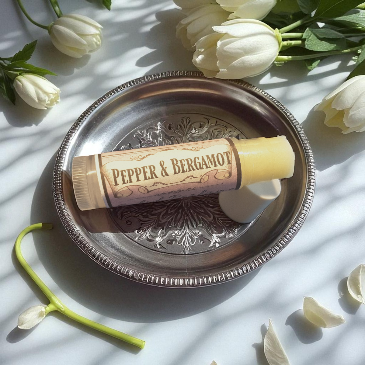 Pepper & Bergamot solid perfume on a decorative silver tray with white tulips around