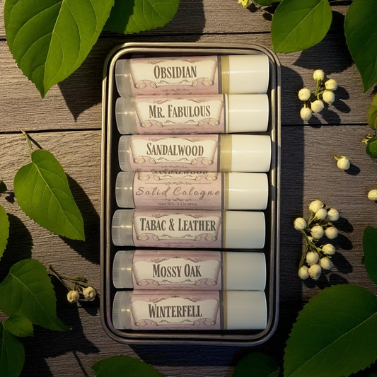 Set of solid cologne sticks with labels on a wooden surface surrounded by leaves and flowers.