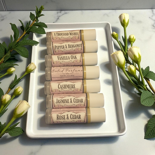 Set of solid perfume sticks on a white tray with flowers on a marble surface