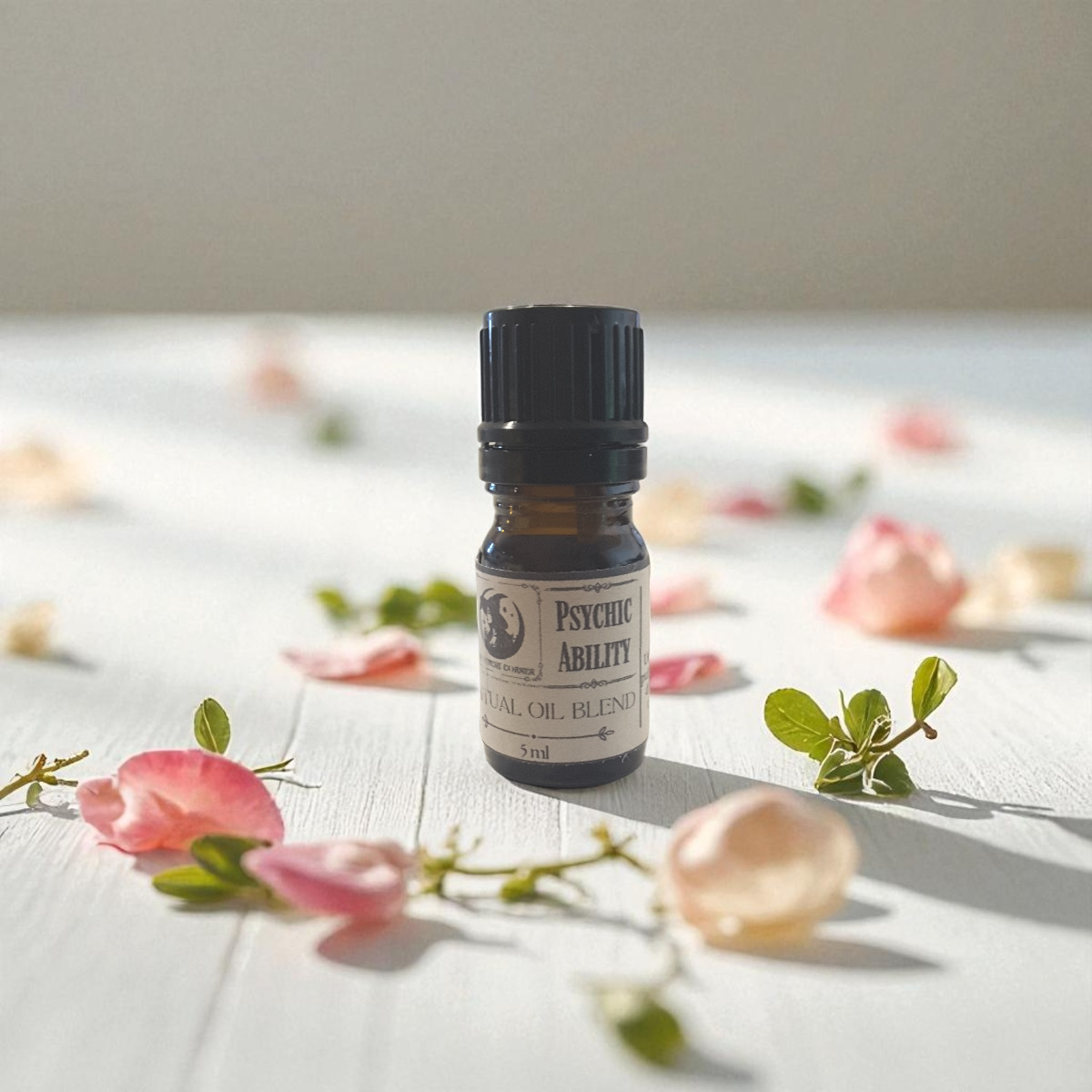 Psychic Ability ritual oil blend on a white surface with flowers and leaves.