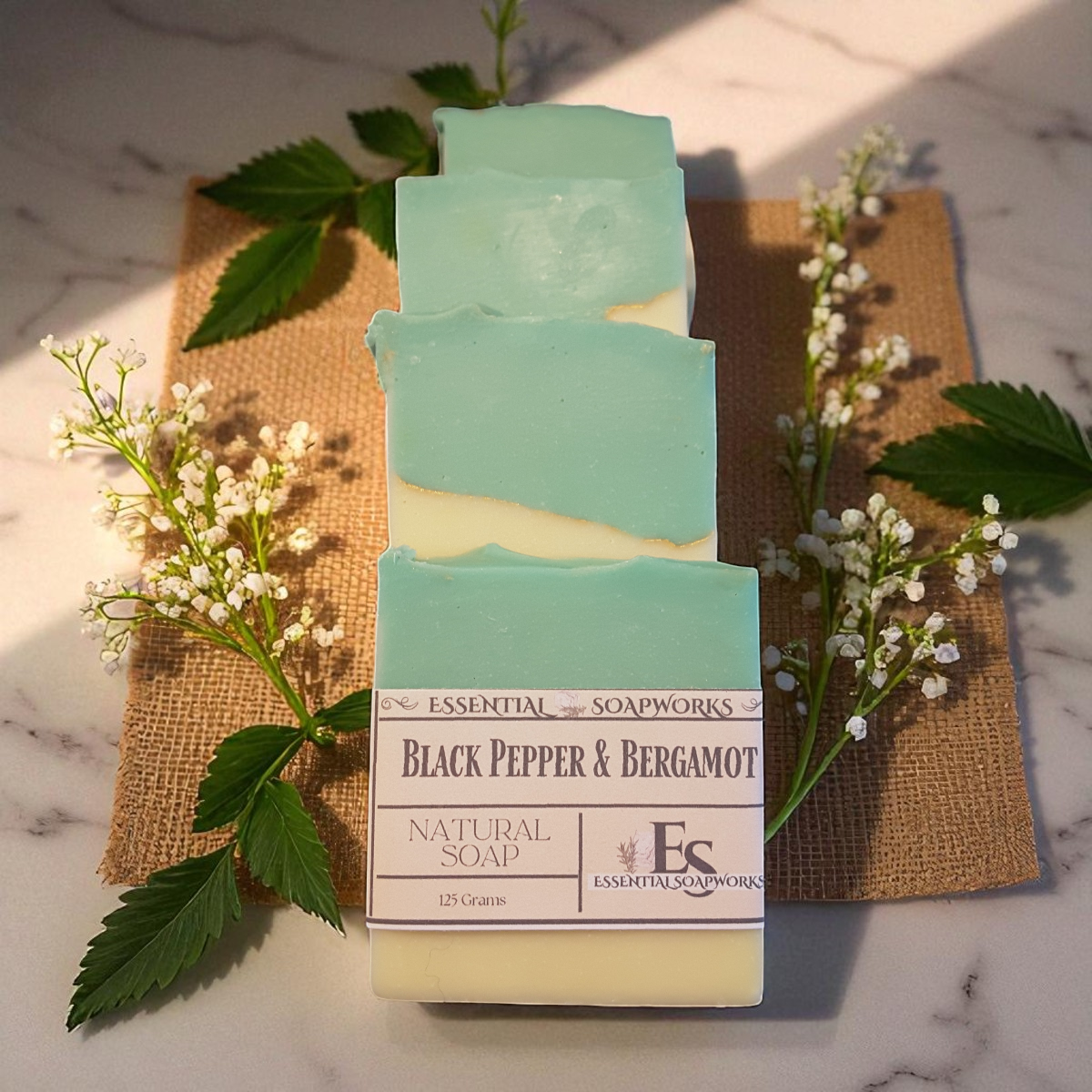 Black Pepper & Bergamot soap on a marble surface with greenery.