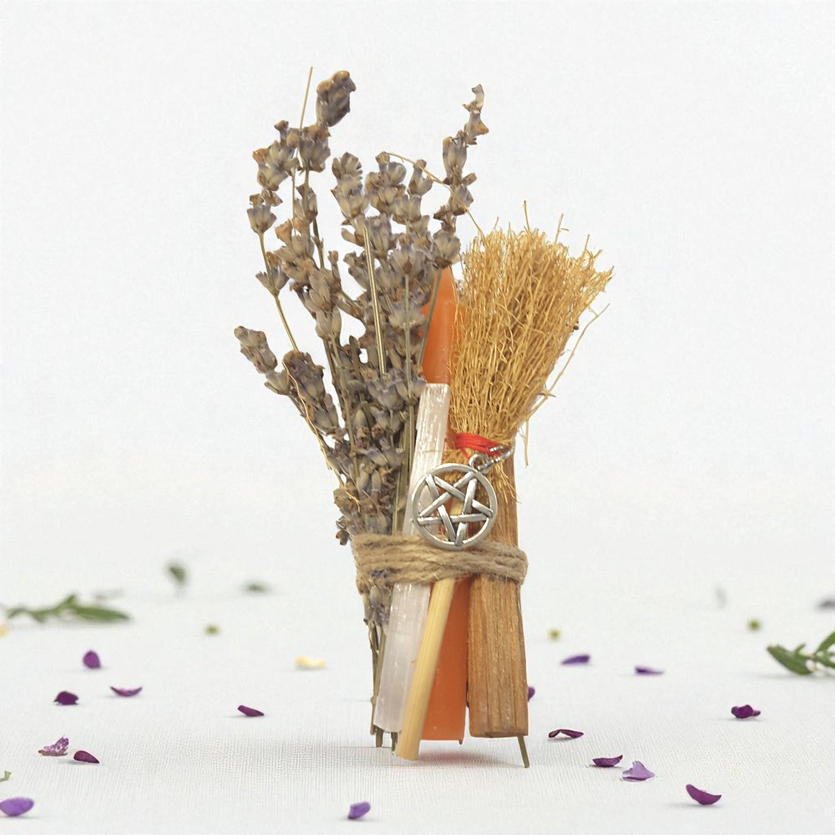 Broom with lavender, selenite, sandalwood, orange chime candle and a pentacle charm on a white background