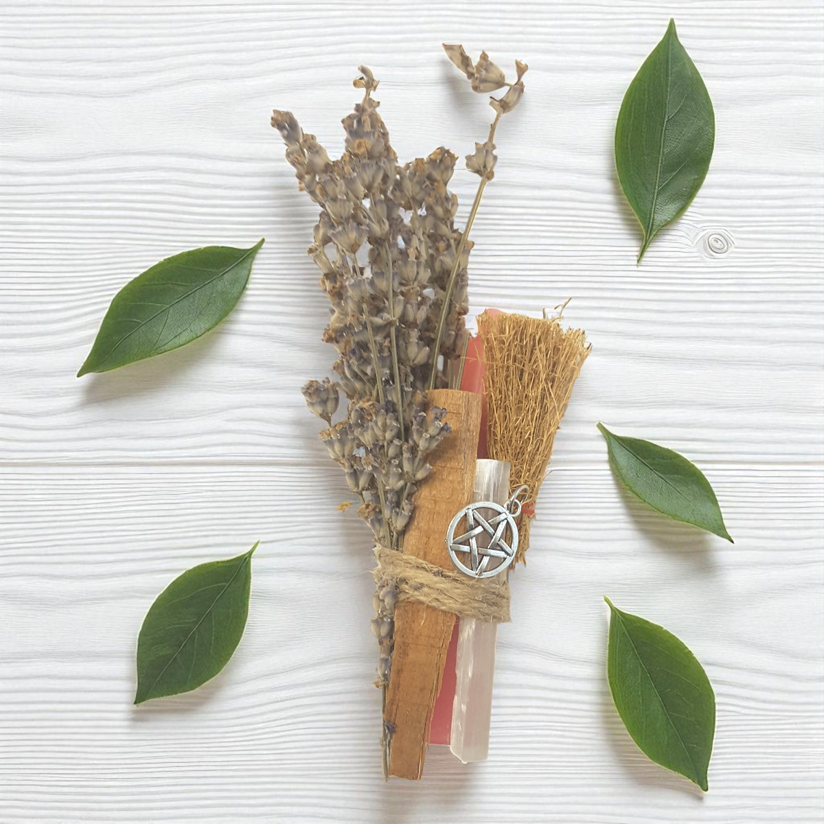 Decorative bundle with lavender, sandalwood, pink chime candle, mini besom, twine, and a pentacle charm on a white background