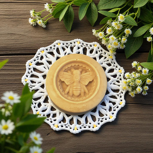 honey bee soap with bee design on a white doily surrounded by flowers on a wooden surface