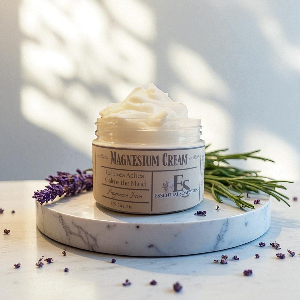Jar of magnesium cream on a marble surface with lavender and rosemary leaves.