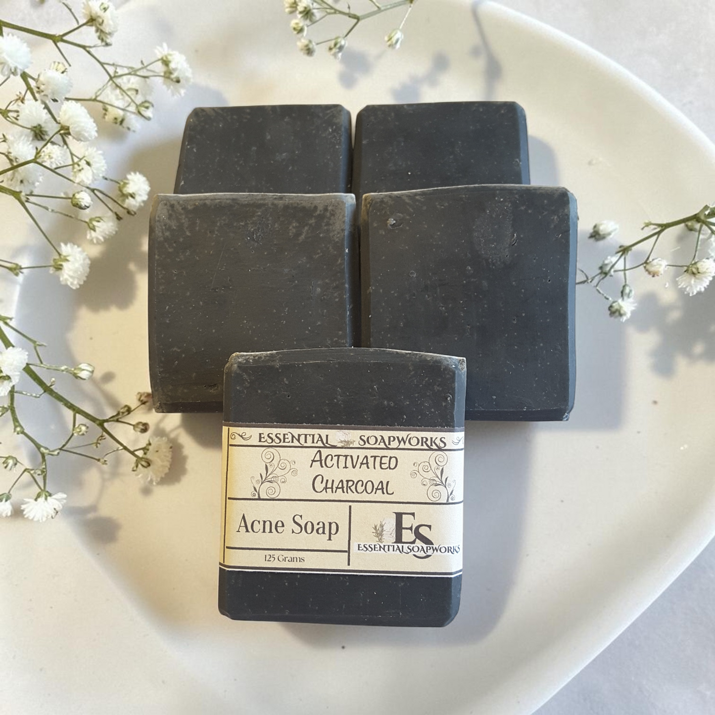 activated charcoal acne soap on a doily on a white surface with white flowers
