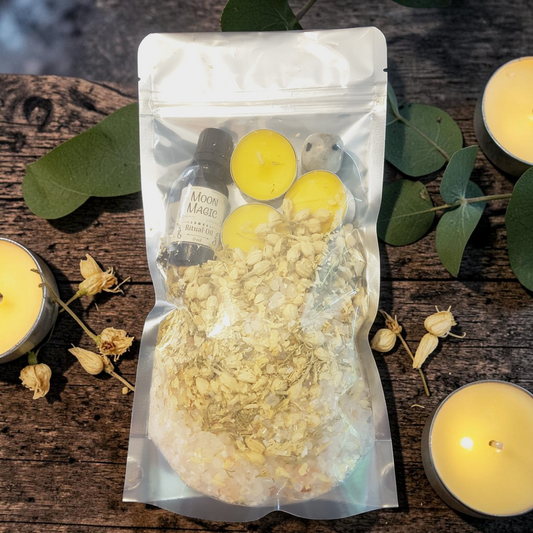 Moon Magic Bath Ritual Kit with bath salts, jasmine, ritual oil, tealight candles and moonstone crystal on a wooden surface