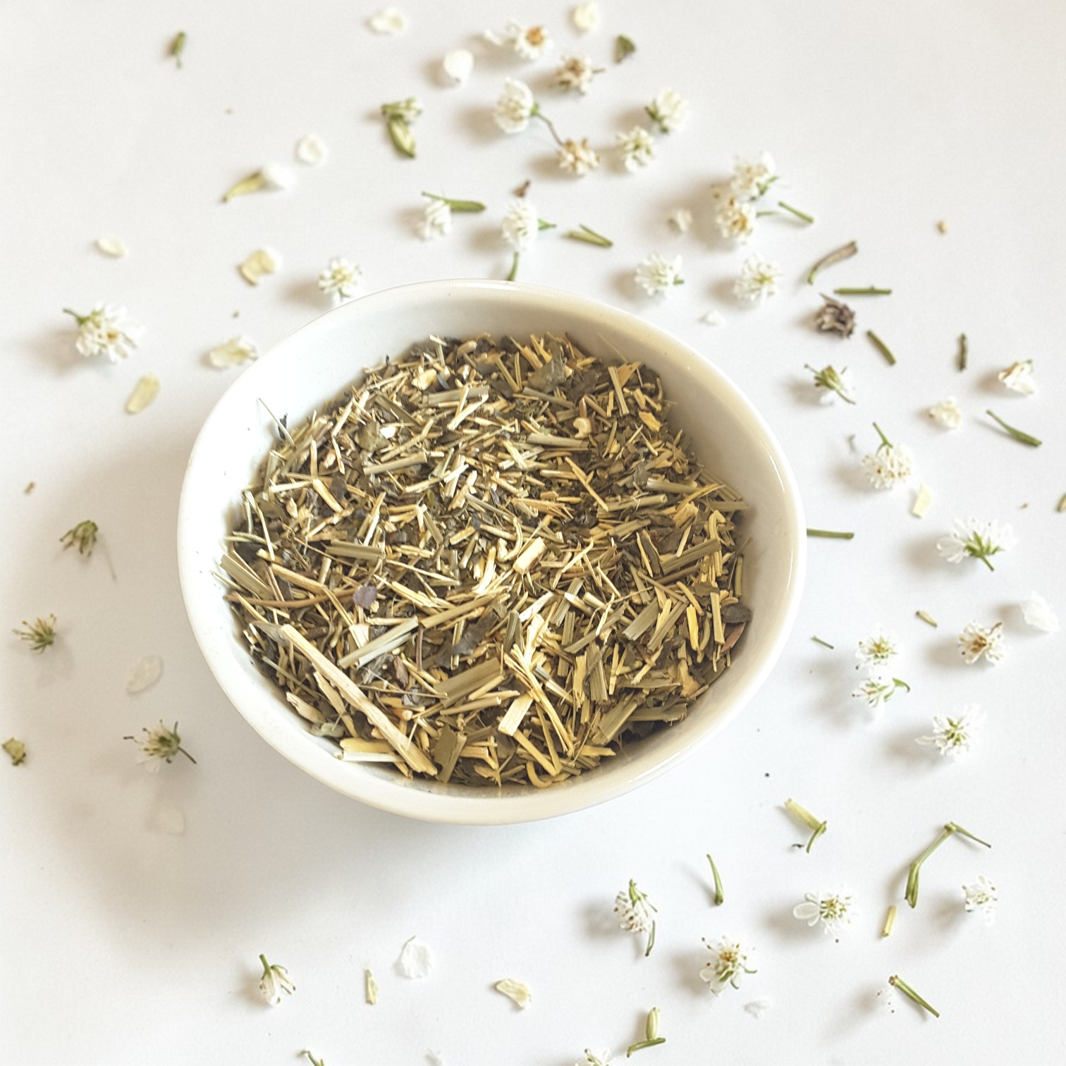 Steady Energy Emotional Wellness Tea on a light background with scattered herbs and flowers.