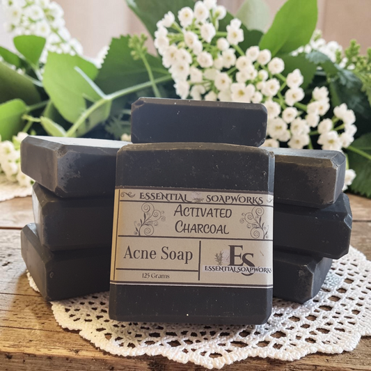 activated charcoal acne soap on a doily on a wooden surface with white flowers