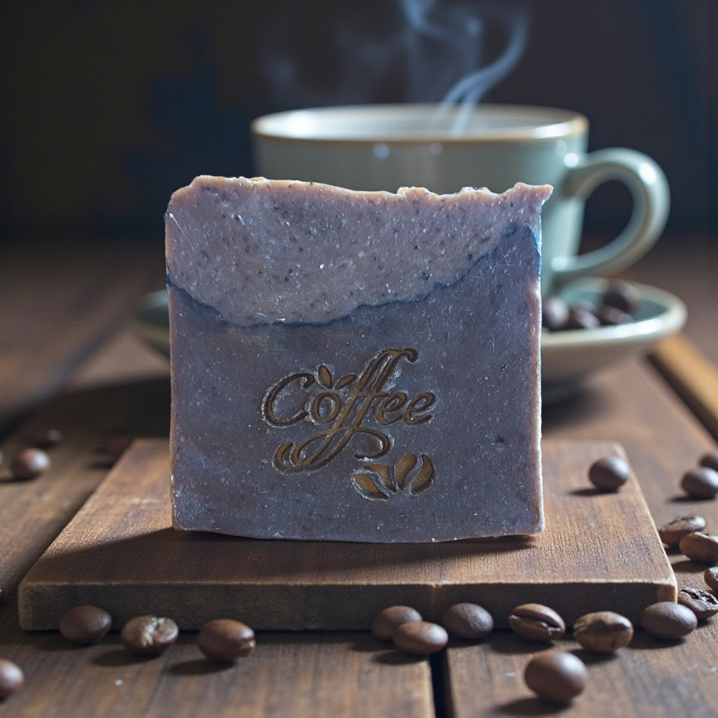 Bar of coffee soap with 'Coffee' text on a wooden board with coffee beans and a steaming cup in the background.