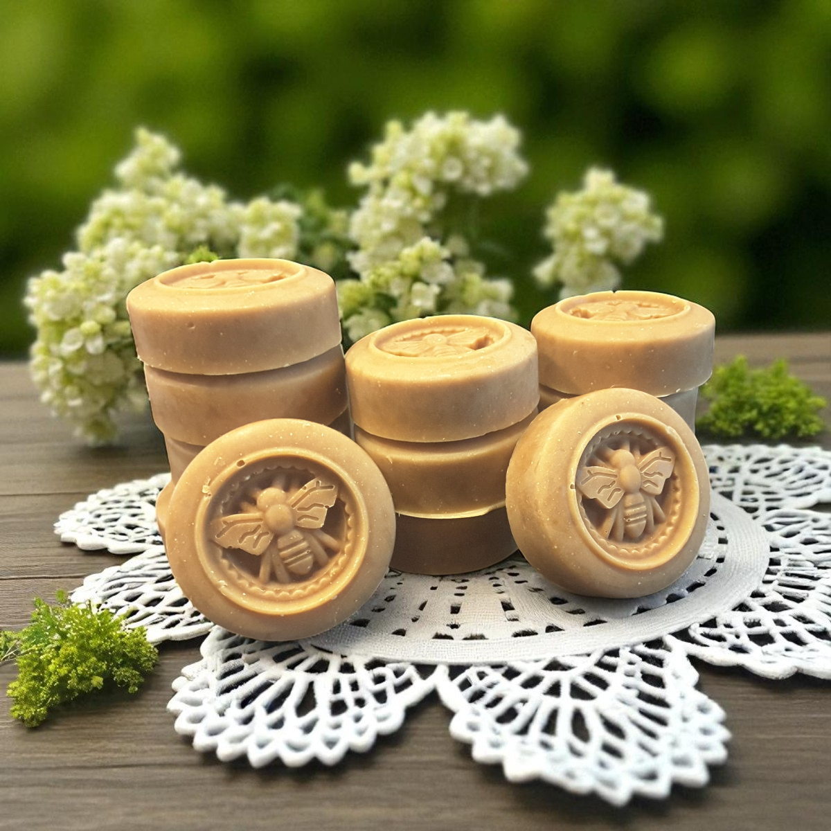 honey bee soaps with bee design on a white doily with flowers in the background