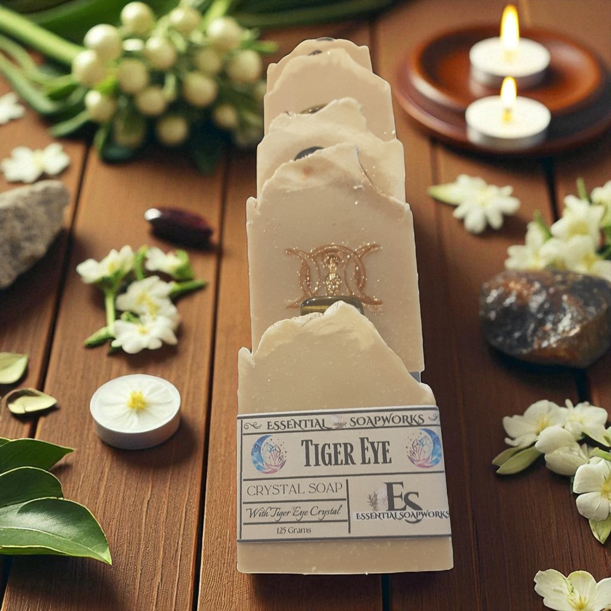 Tiger Eye crystal soap with a triple goddess symbol on a wooden surface with flowers and candles.