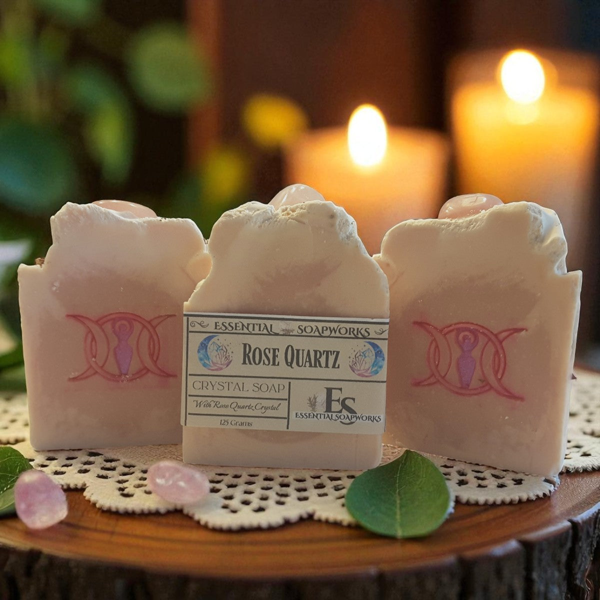 Rose Quartz crystal soap with a triple goddess symbol on a wooden surface with candles in the background