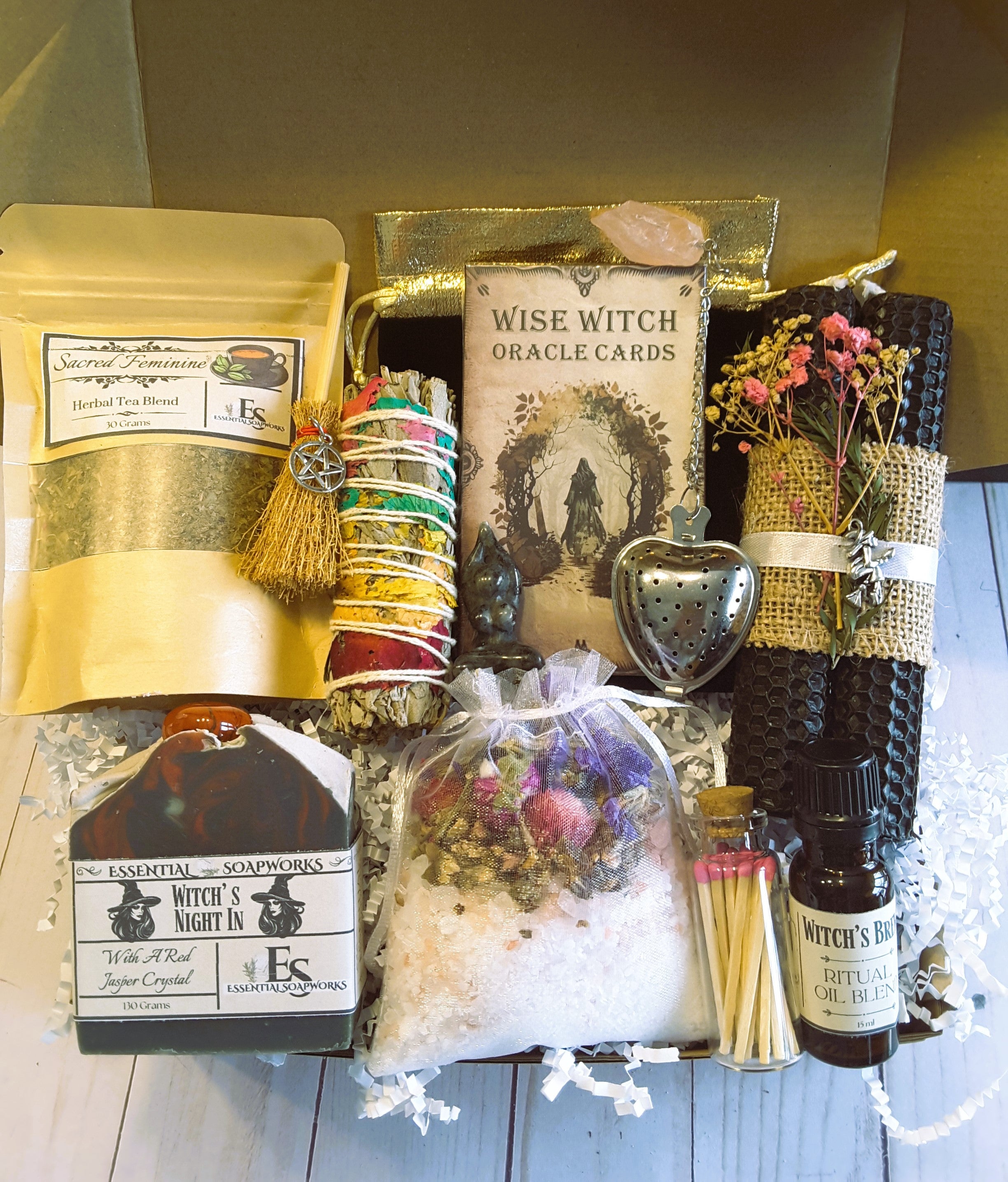 Collection of witchcraft-themed items including tea, cards, and oils on a wooden surface.