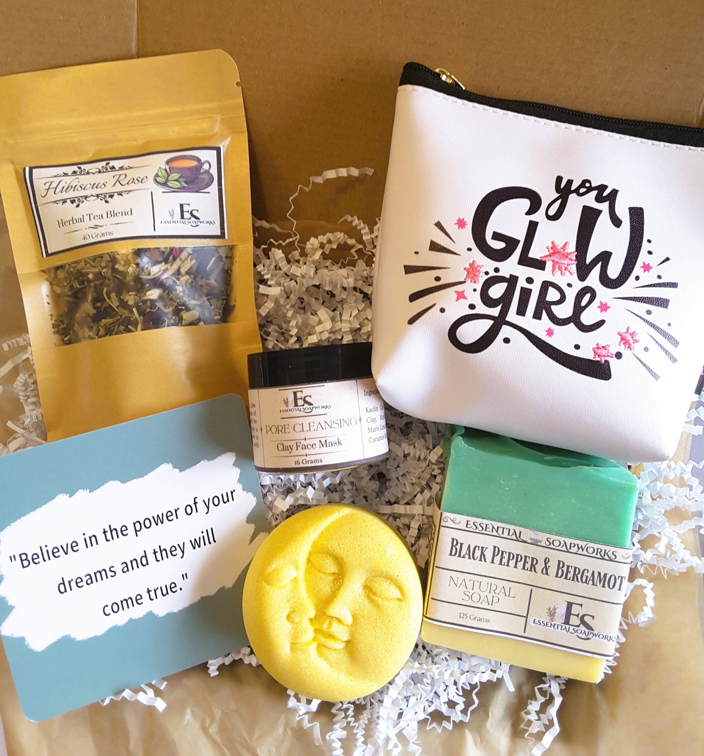 Holistic Self-Care Mystery Kit including a pouch, tea blend, face mask, soap, and motivational card on a textured surface.