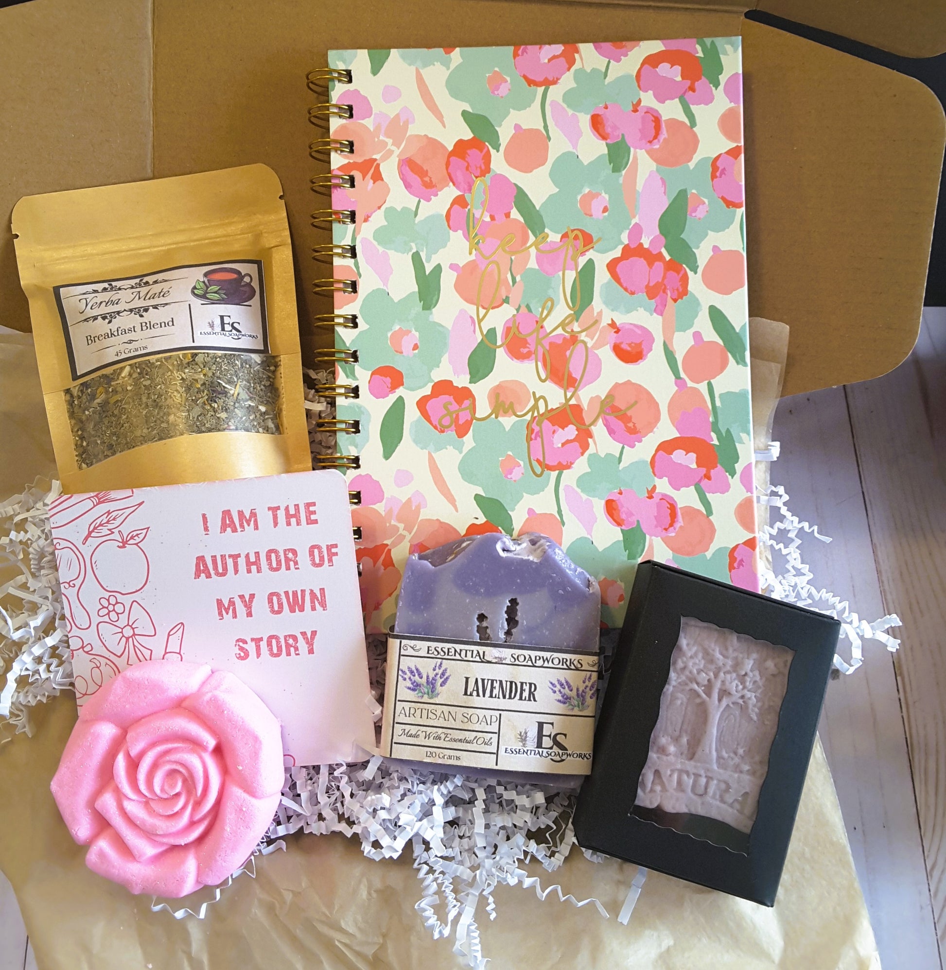 Holistic Self-Care Mystery Kit with a floral notebook, soap, and other items on a wooden surface