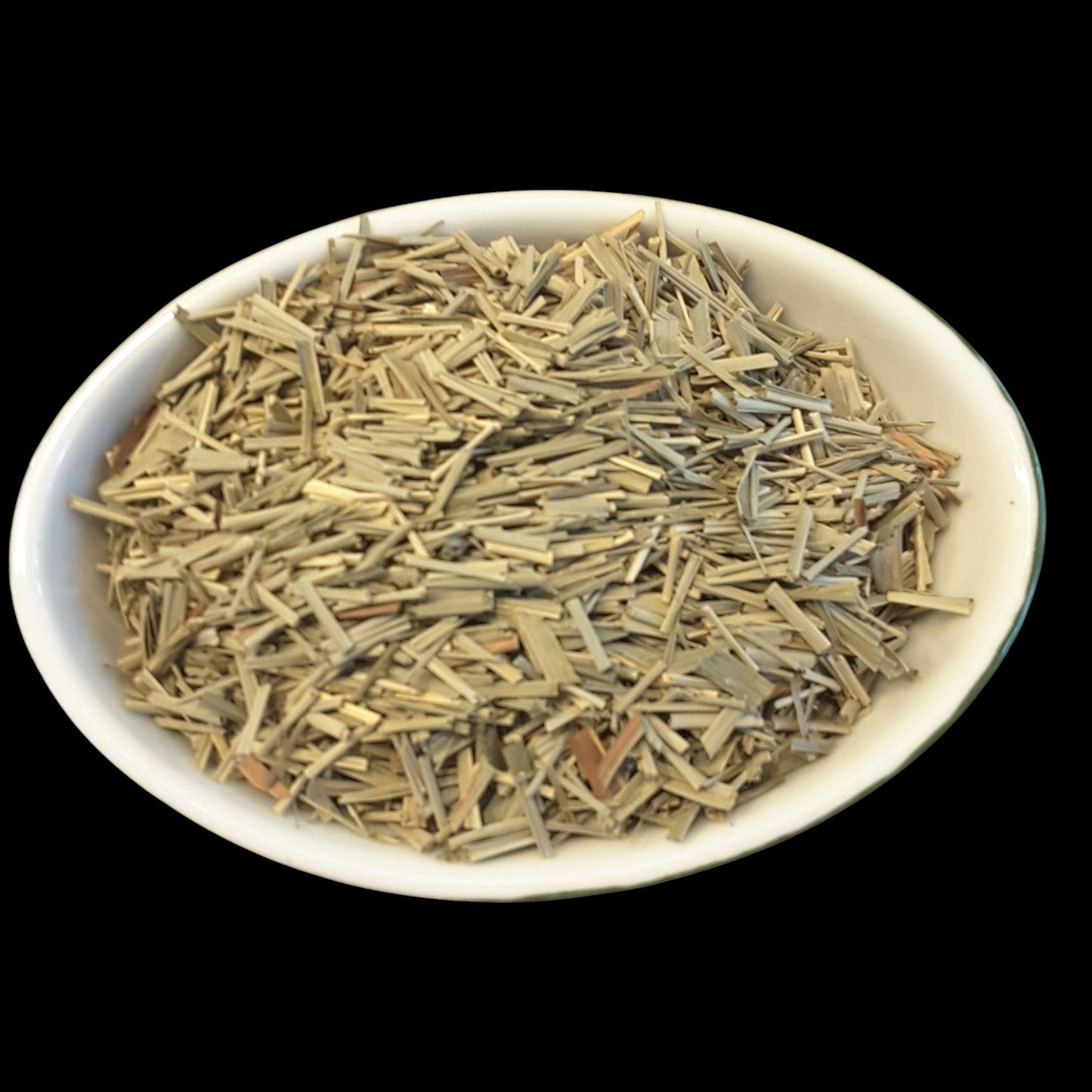 A white oval bowl filled with lemongrass photographed against a solid black background.