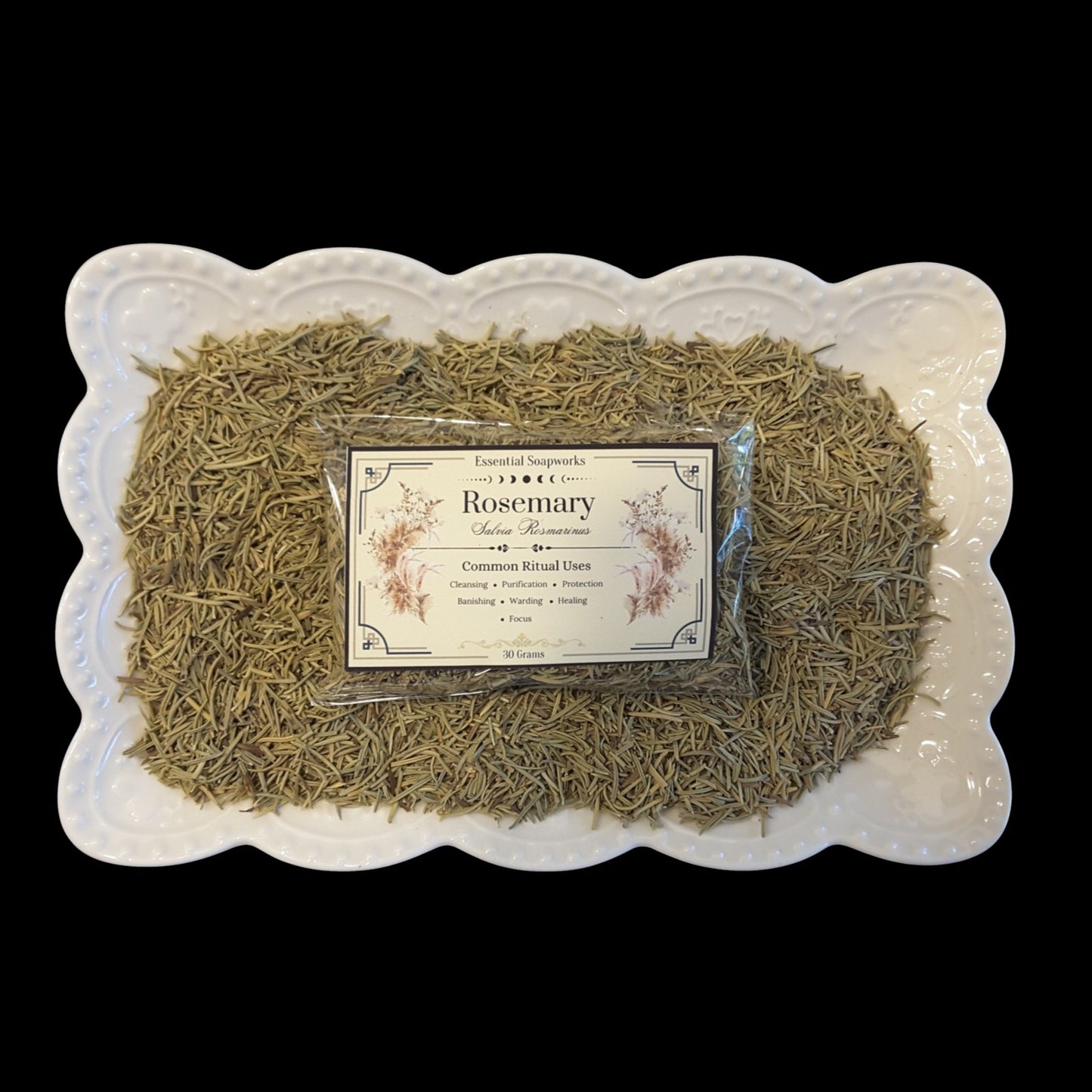 a package of dried rosemary on a bed of rosemary in a white dish on a black background