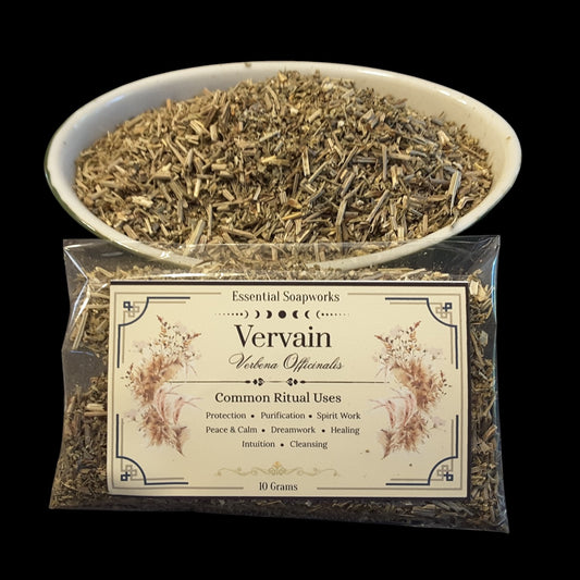 A clear plastic bag of Vervain Herb for witchcraft with a cream label, shown in front of a white bowl filled with dried vervain herb pieces on a black background.