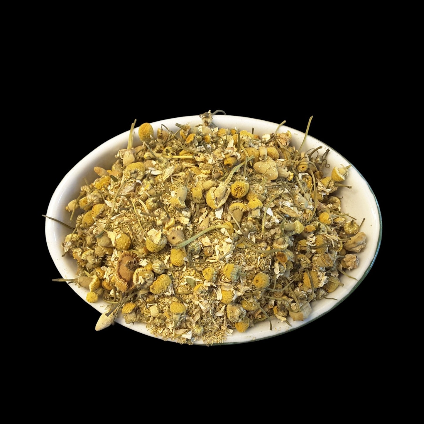 A white oval bowl filled with loose dried chamomile flowers against a solid black background.