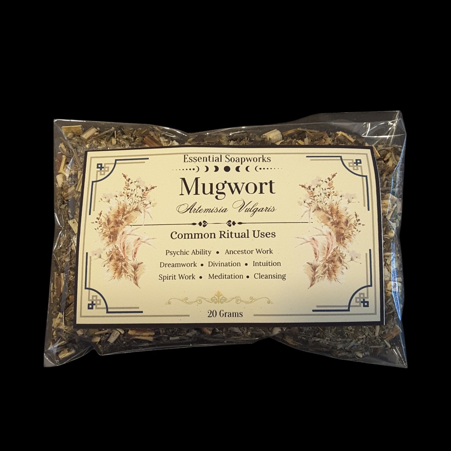 A clear plastic bag of mugwort leaves, with a cream-colored label detailing common ritual uses, set against a solid black background.