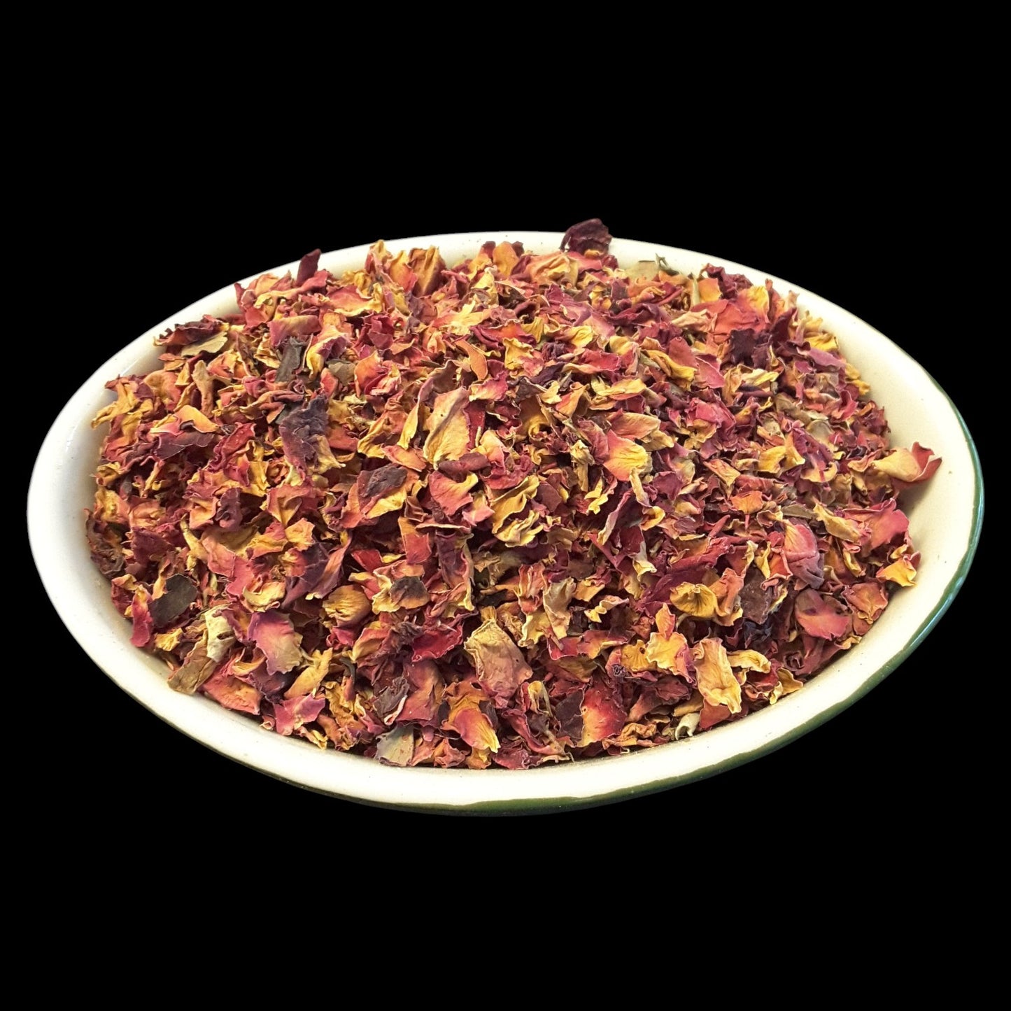 A white oval bowl filled with dried rose petals, photographed against a solid black background.