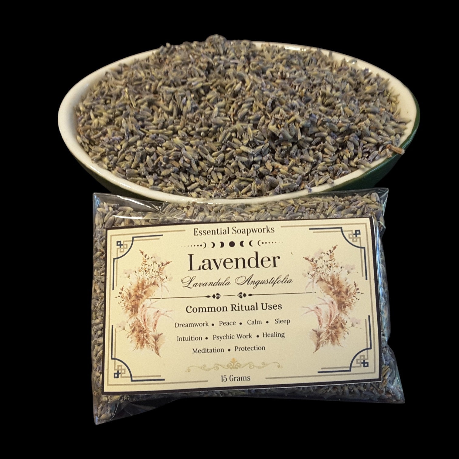 A clear plastic bag of lavender buds with a cream label reading 'Lavender' and 'Essential Soapworks,' placed in front of a white bowl filled with dried lavender buds on a black background.