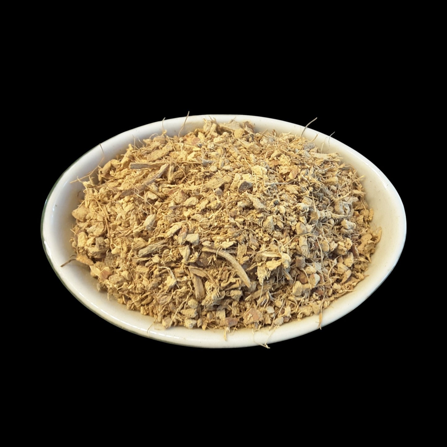 A white oval bowl filled with a mound of galangal root photographed against a solid black background.
