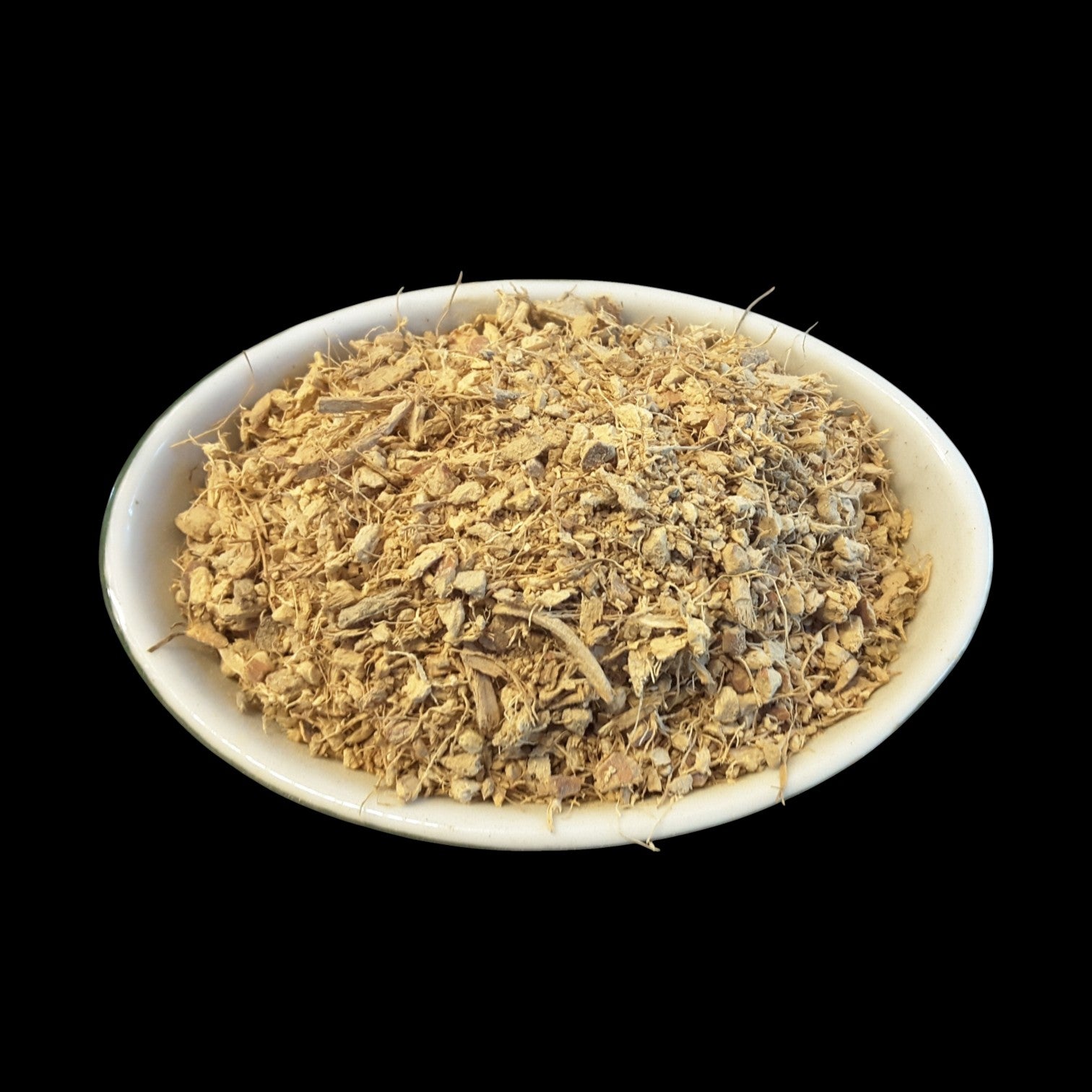 A white oval bowl filled with a mound of galangal root photographed against a solid black background.