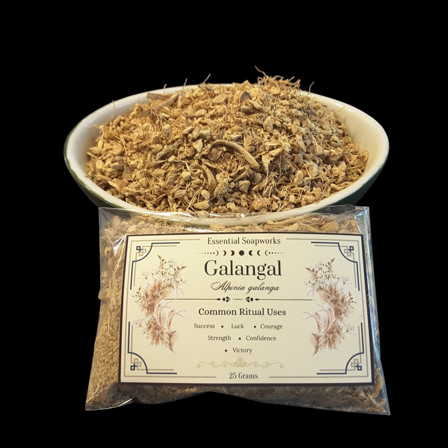 A clear plastic bag of  Galangal Root shown in front of a white bowl filled with dried galangal roots against a solid black background.