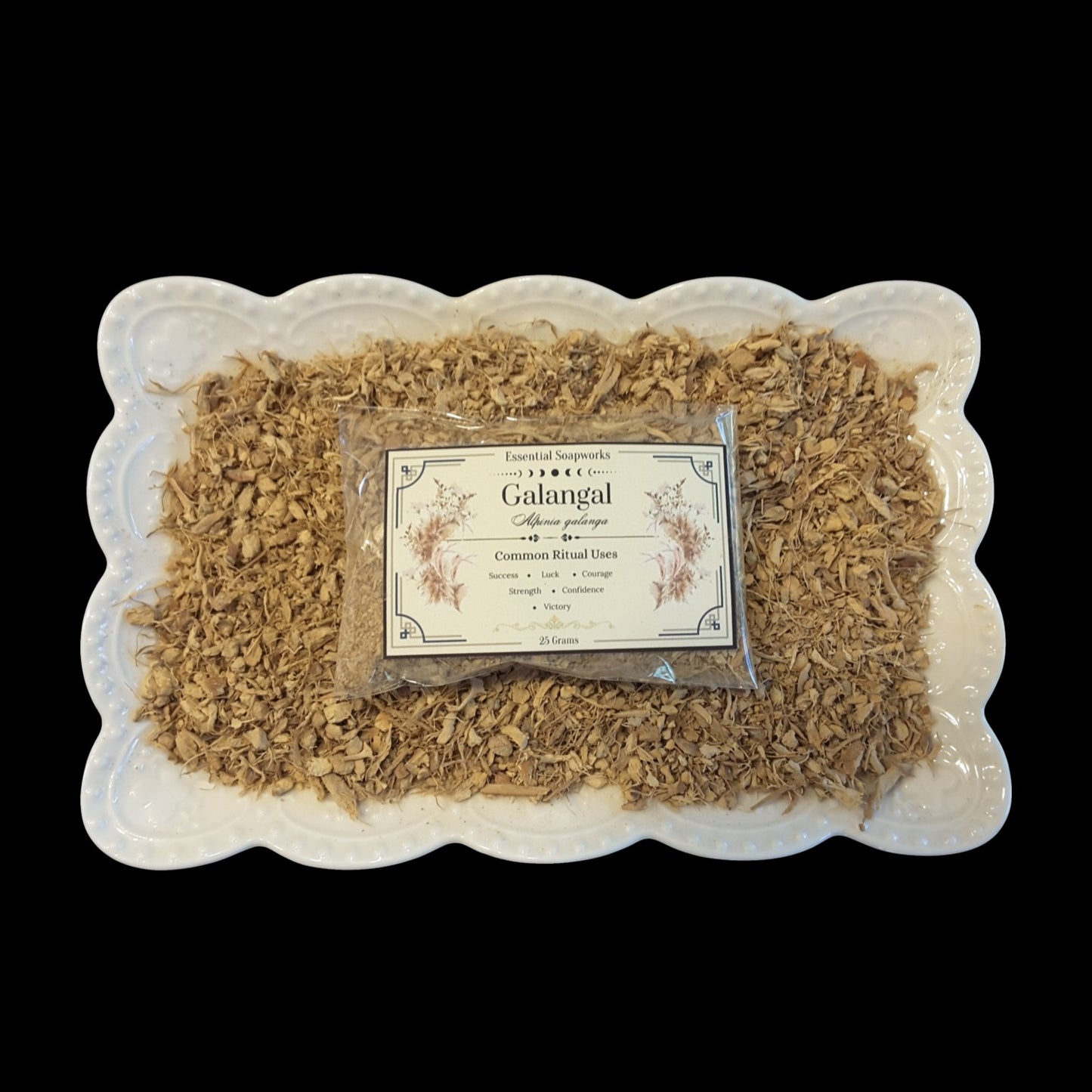 A clear plastic pouch of Galangal root arranged on a white scalloped ceramic platter against a solid black background.