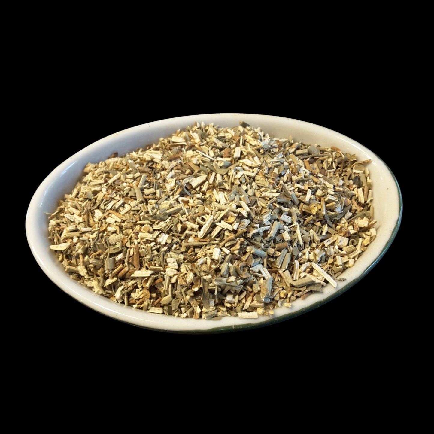 A white oval dish filled with rue herb photographed against a solid black background.