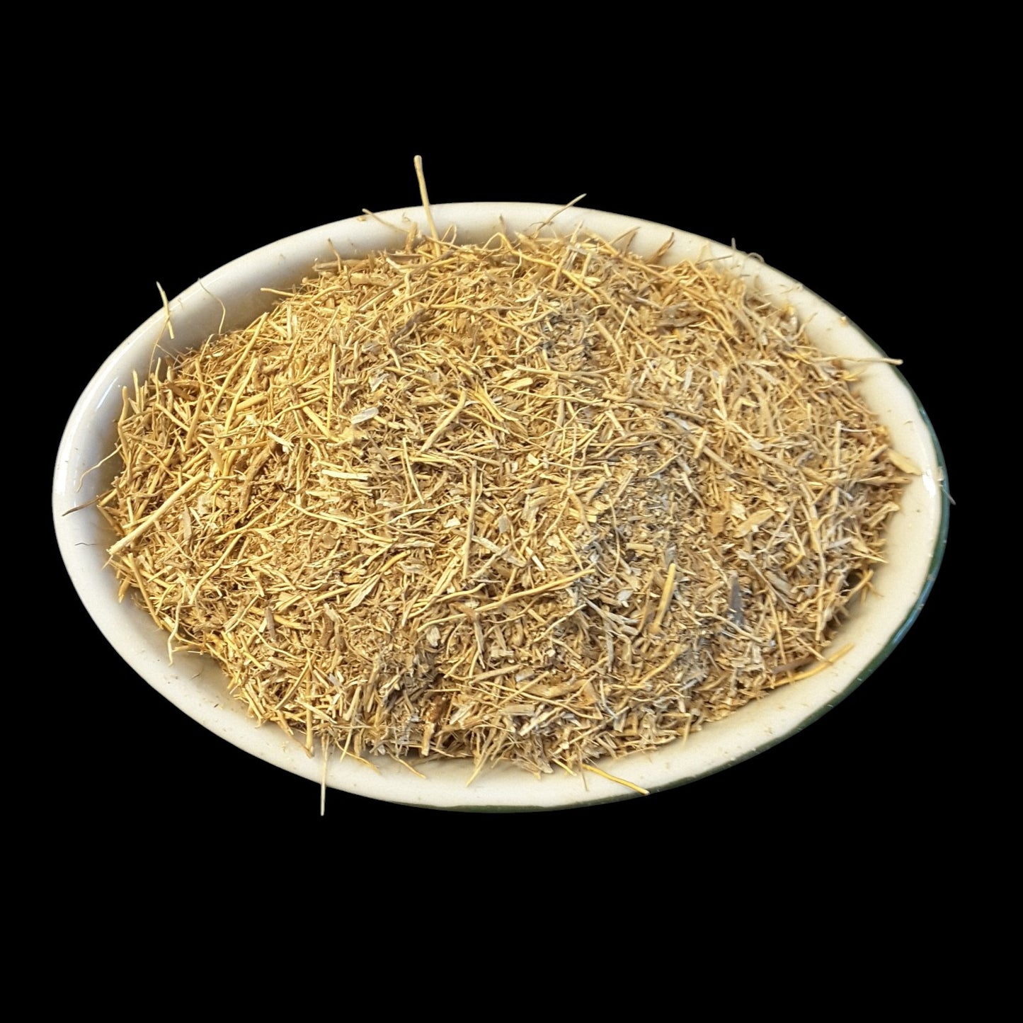 A white oval dish filled with dried vetiver root photographed against a solid black background.