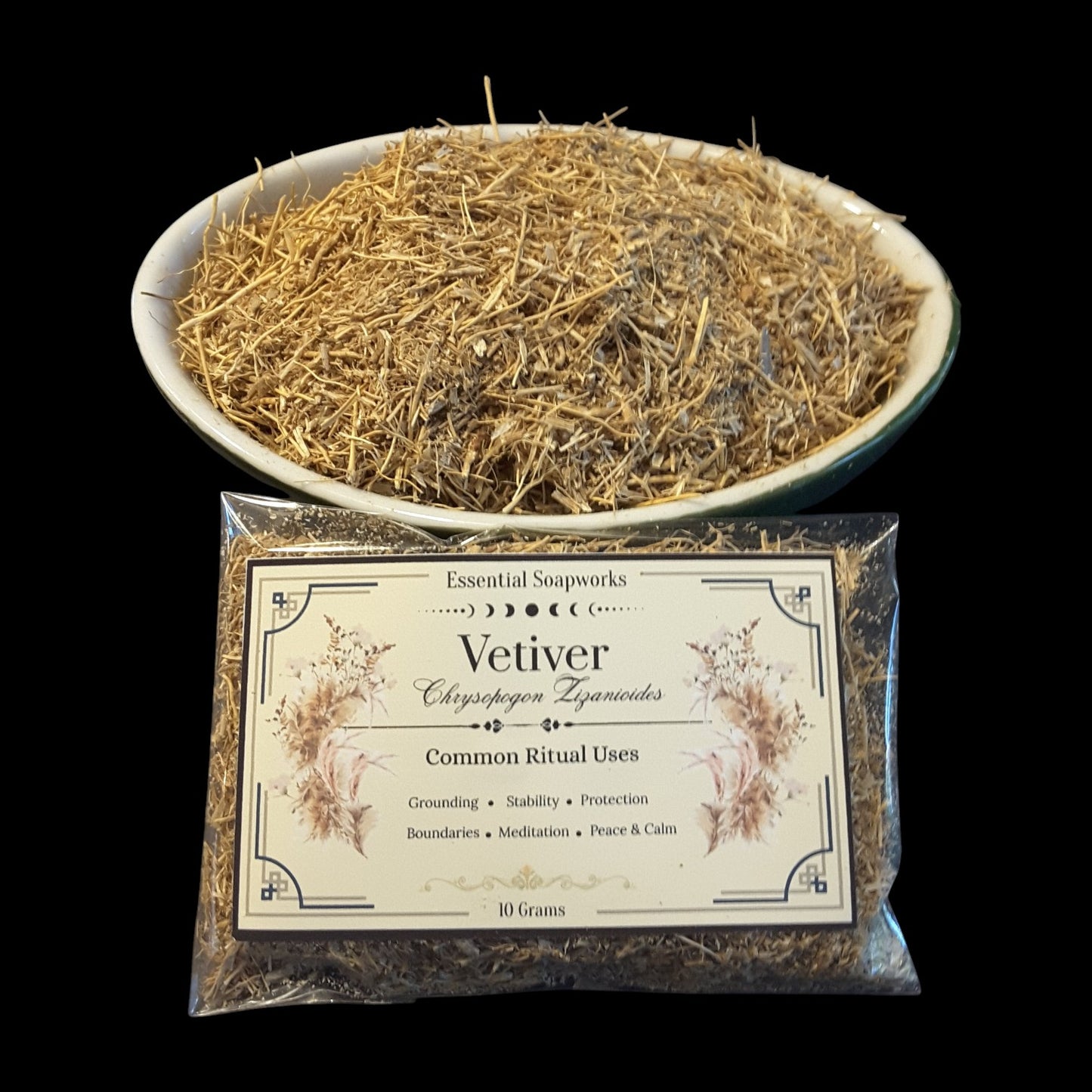 A clear plastic bag of Vetiver root placed in front of a white bowl filled with dried yellowish-brown vetiver roots on a solid black background.