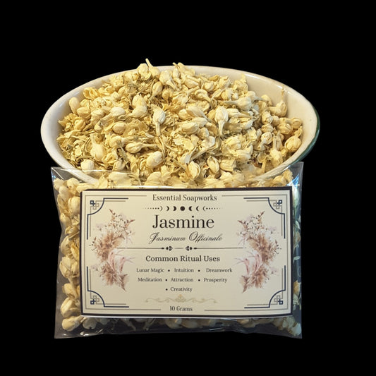 A clear plastic bag of Essential Soapworks Jasmine (Jasminum Officinale) 10 grams, with a white bowl filled with dried pale yellow jasmine buds placed behind it, set against a solid black background.