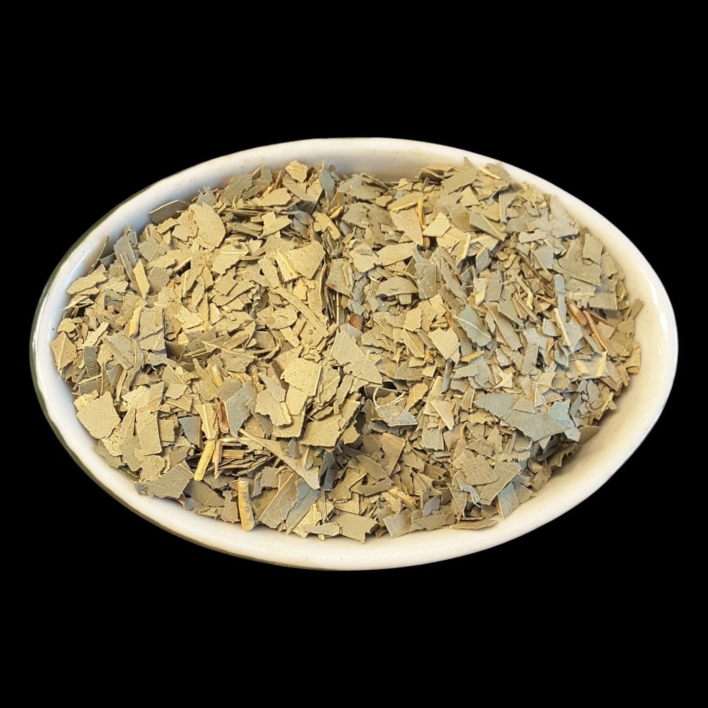 Dried eucalyptus presented in a white oval ceramic bowl against a solid black background.