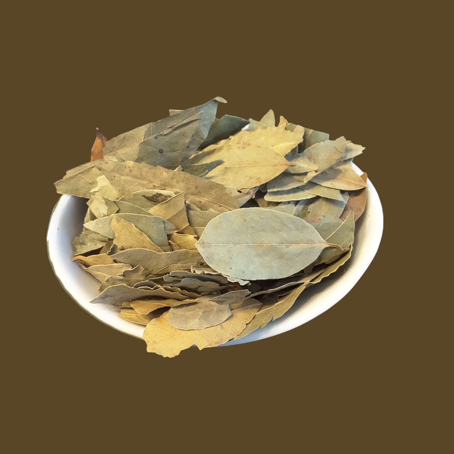 A pile of dried bay leaves in shades of olive green, tan, and brown, piled in a small white bowl against a solid dark brown background.