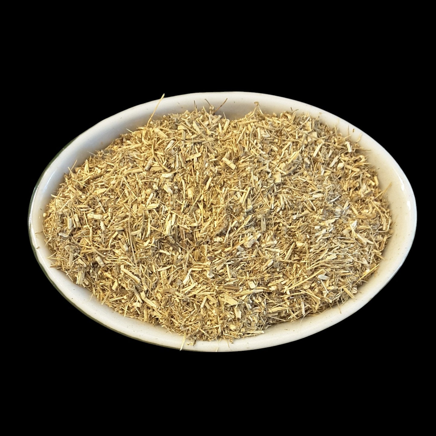 A white oval bowl filled with dried wormwood for witchcraft photographed against a solid black background.