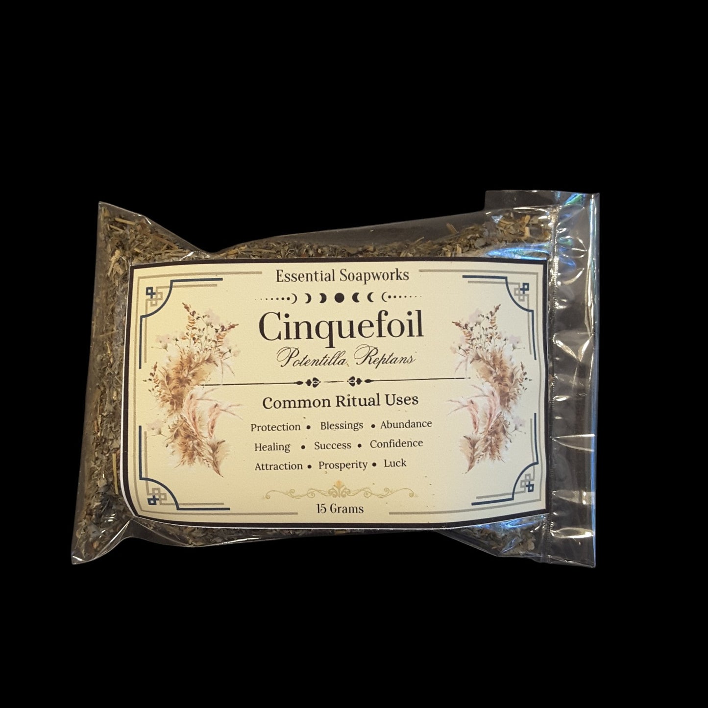 A 15g package of Essential Soapworks Cinquefoil, sealed in a clear plastic bag with a decorative cream-colored label, set against a solid black background.