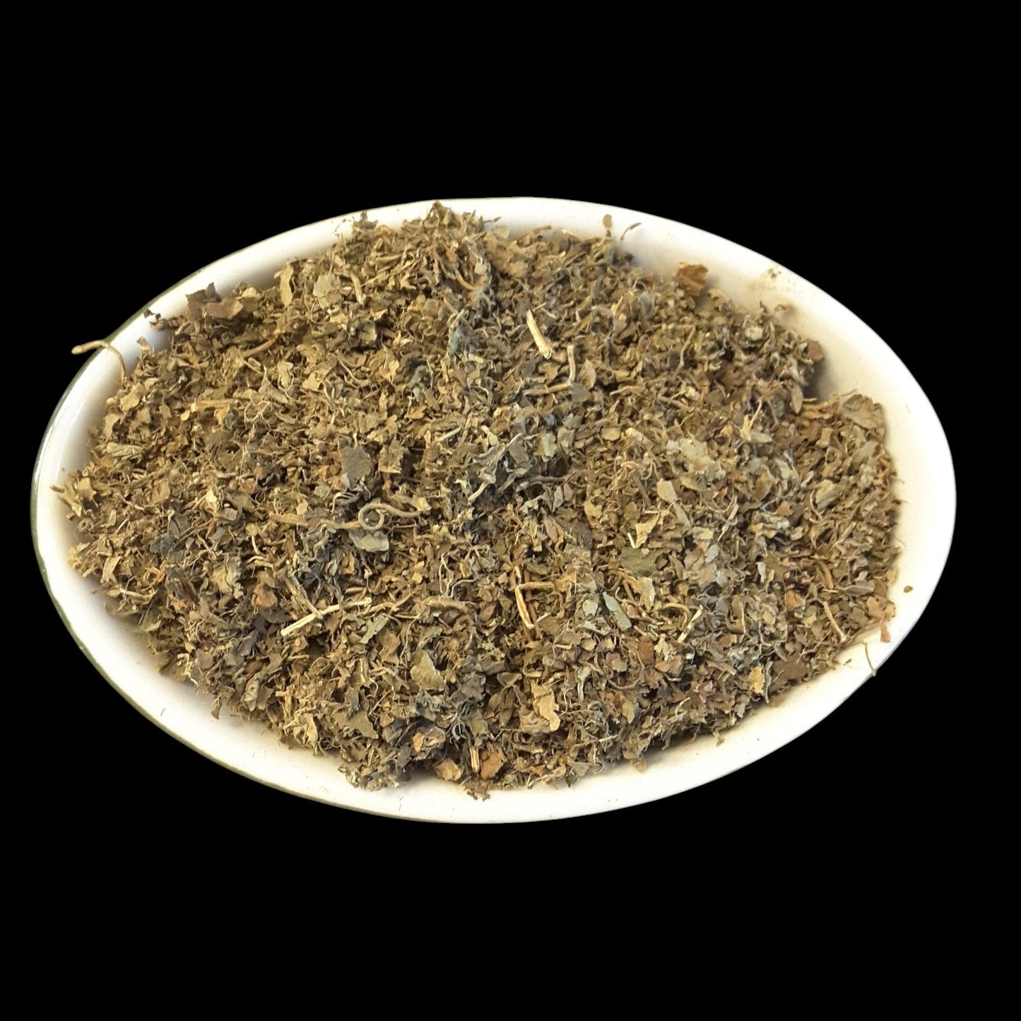 A white oval dish filled with patchouli herb photographed against a solid black background.