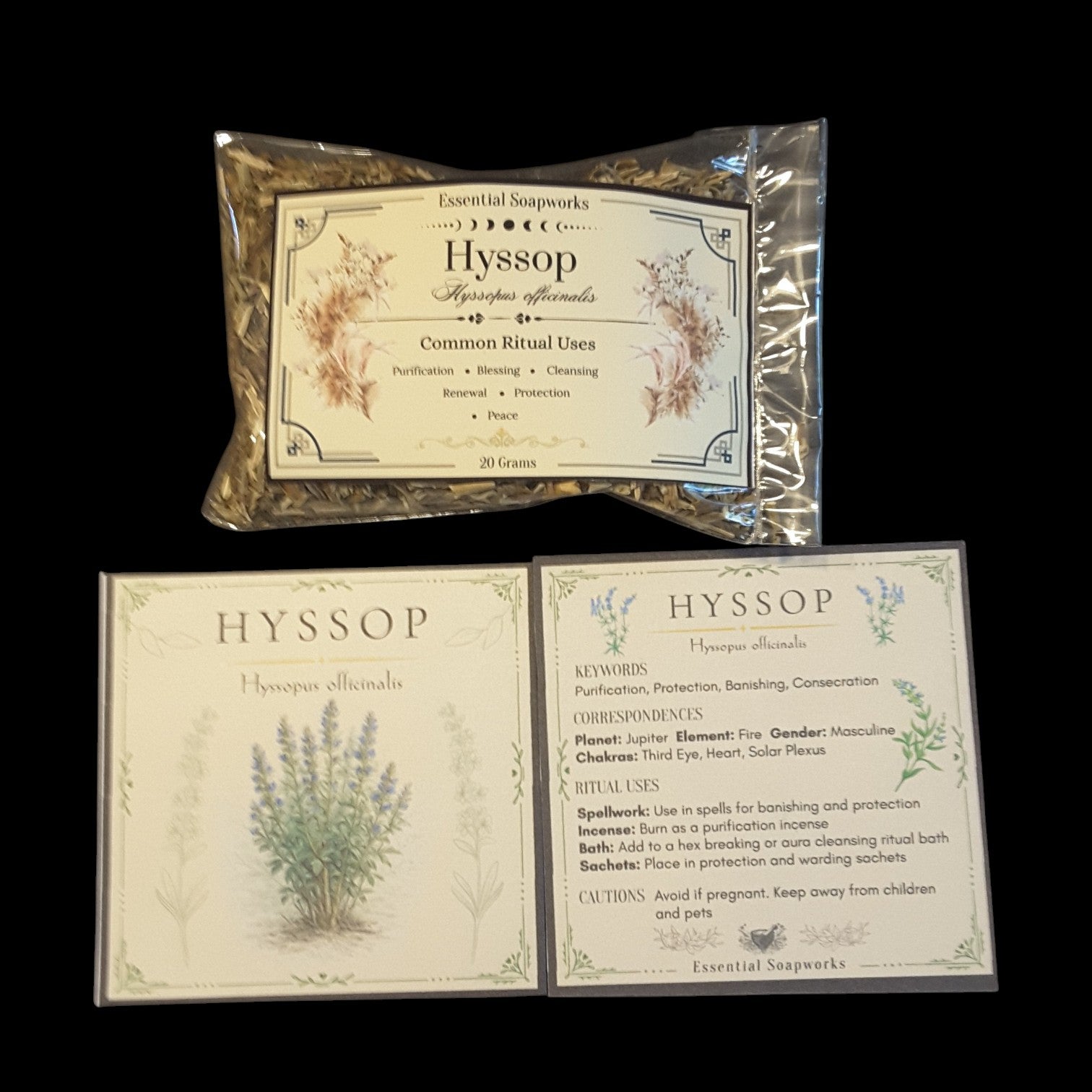 Two Essential Soapworks Hyssop (Hyssop officinalis) ritual cards and a package of dried hyssop displayed on a solid black background. The set includes a clear plastic bag containing hyssop with a label, and two separate square cards showing detailed instructions, keywords, and spiritual meanings for the product.